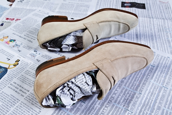 Beige suede loafers stuffed with newspaper for dehumidification