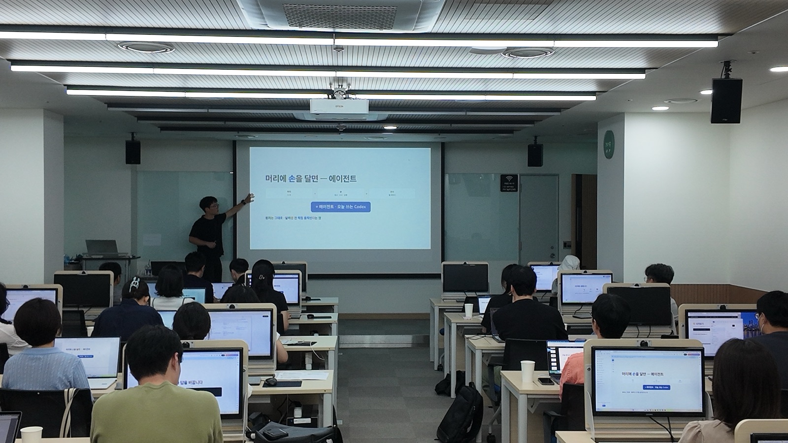 공통교육 2회차 강의실에서 강사가 화면을 가리키며 설명하고 직원들이 각자 PC로 실습하는 모습