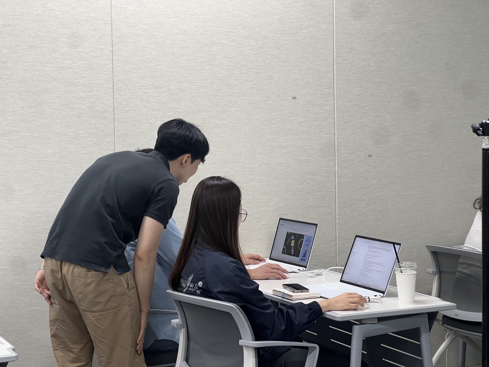 AI 기초 과정 실습 시간에 보조강사가 수강생 옆에서 화면을 함께 보며 지원하는 장면
